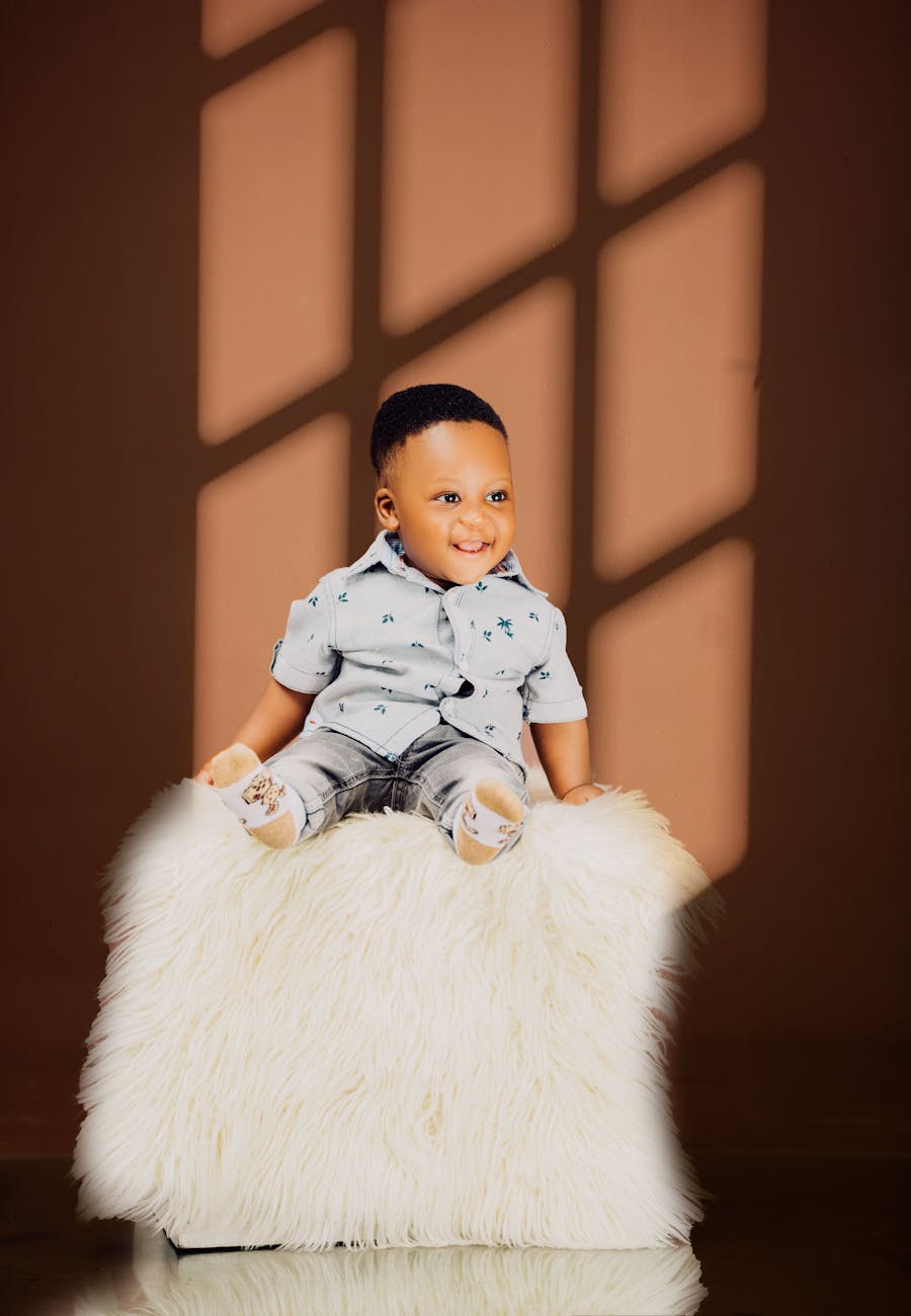 adorable baby seated on a soft white fur stool